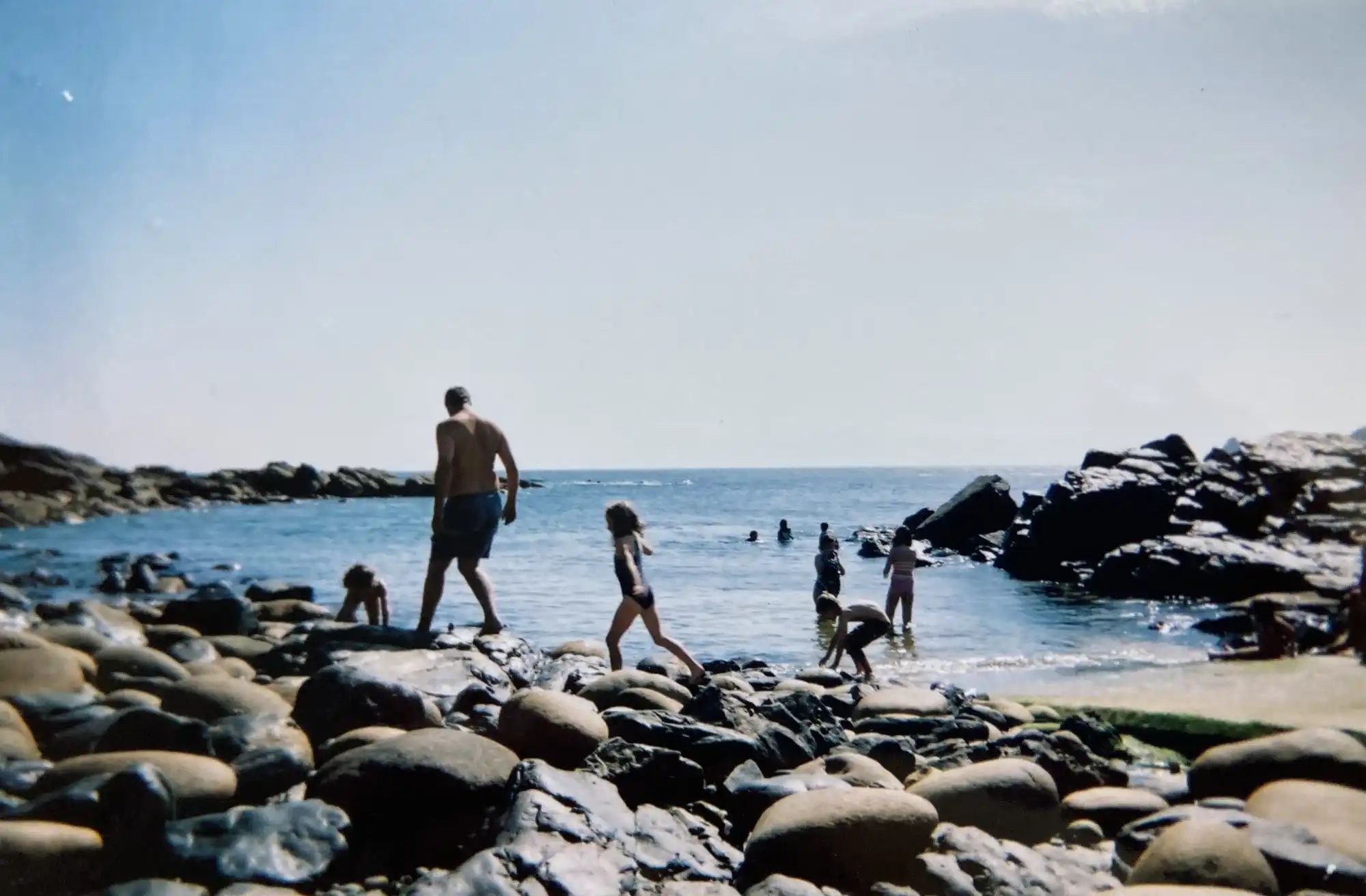 An photo of a rocky shoreline with children playing