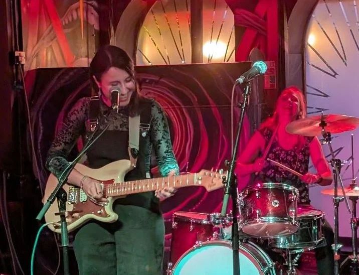 Grainy photo of me (drums) and my bandmate (guitar) on stage